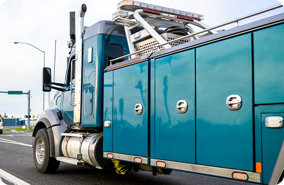 The side and cab of a heavy duty rotator driving down a street
