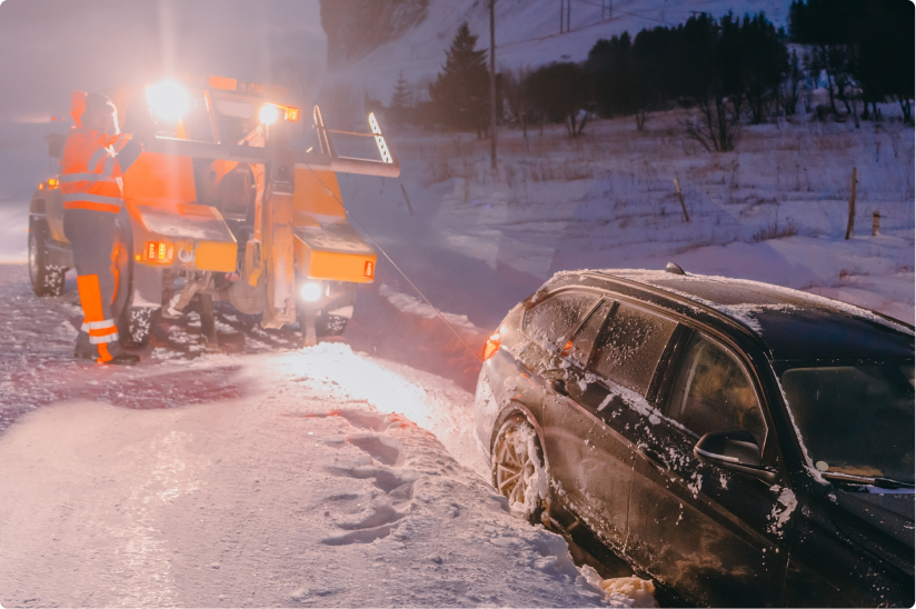 Vehicle stuck in snow in the dark with tow truck providing service
