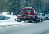 Government towing incident in action with police and tow truck driver working together to tow a vehicle off the side of a snowy road